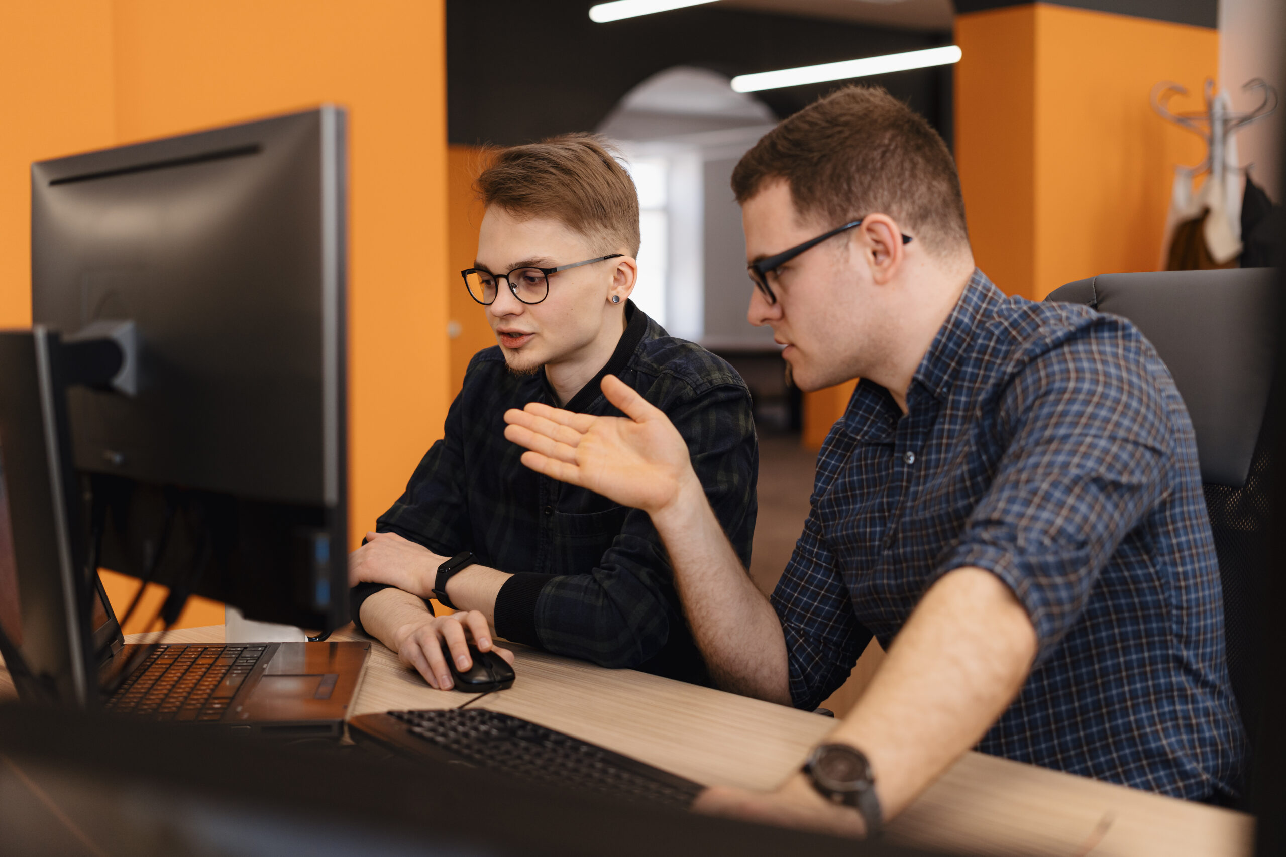 Full concentration at work. Group of young business people working and communicating while sitting at the office desk together with colleagues sitting in the background