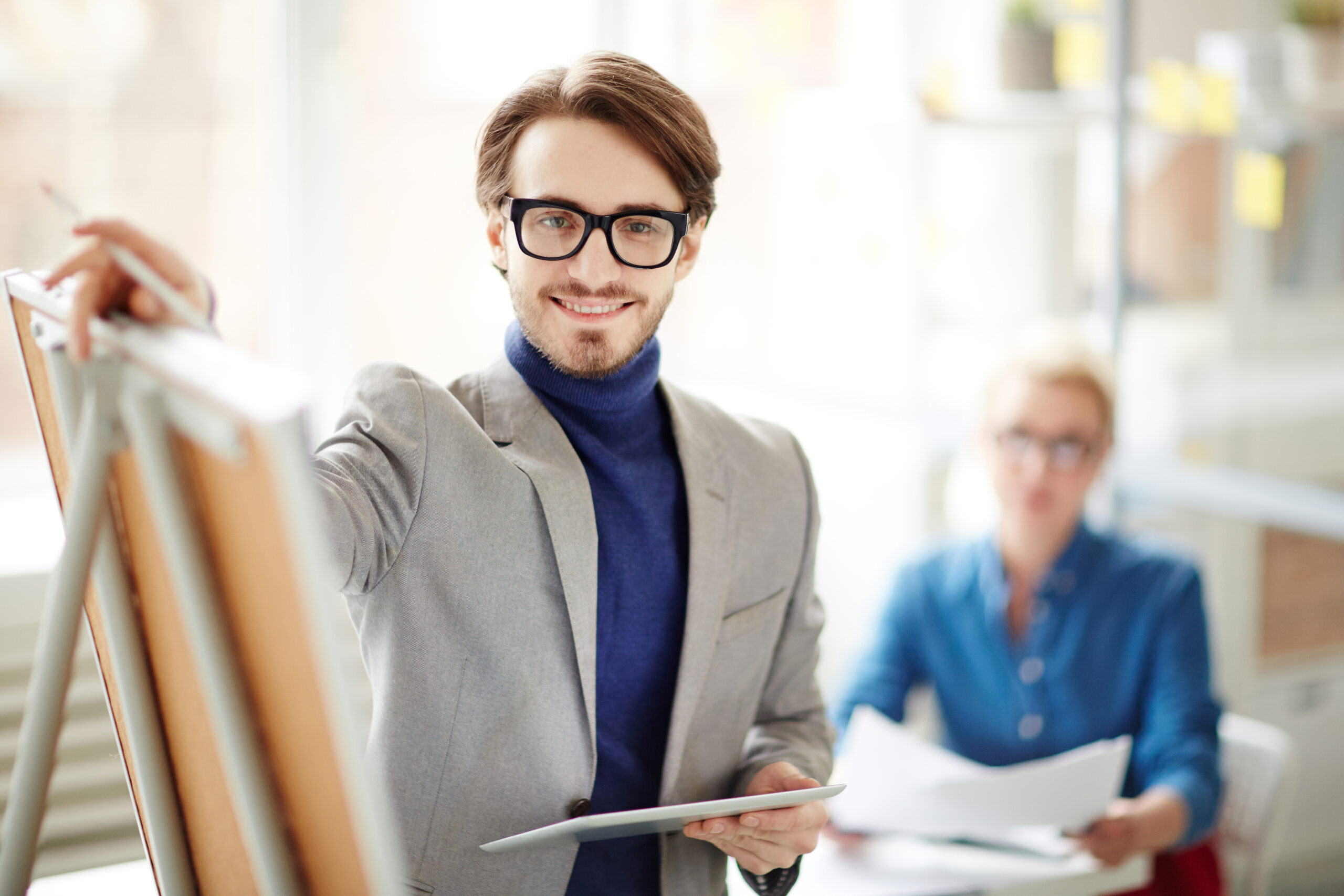 Successful coach standing by whiteboard at business seminar and presenting his viewpoint of modern marketing development